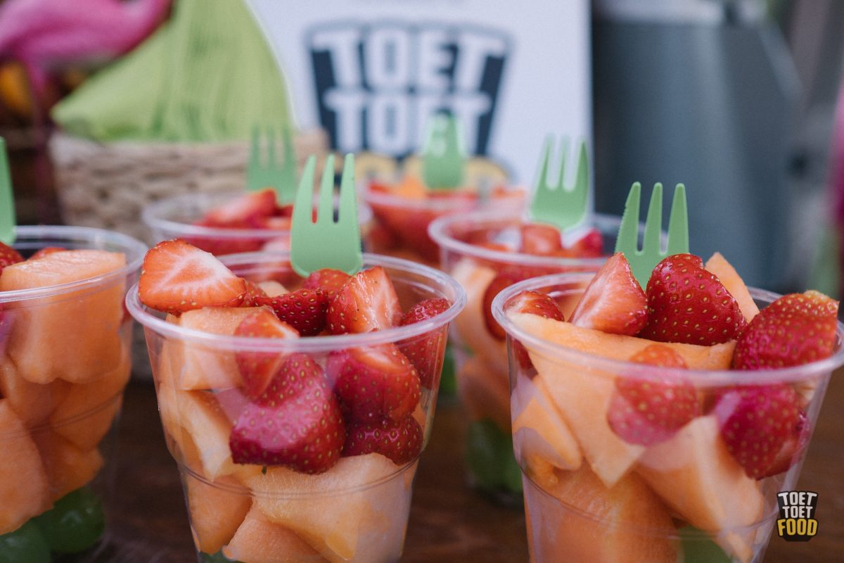 Fruitsalade als Traktatie op Kantoor bekers gevuld met vers gesneden fruit, waaronder aardbeien en meloen